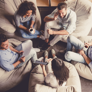 &quot;En gruppe mennesker som sitter på puff og prater mens de drikker kaffe.  &quot;