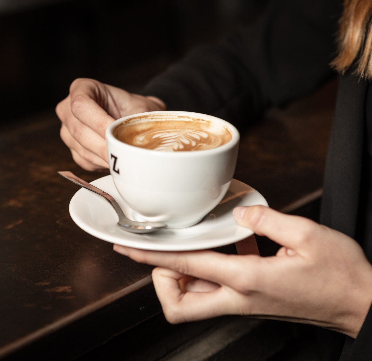 Kvinna håller i en Zoégas kopp med cappucino