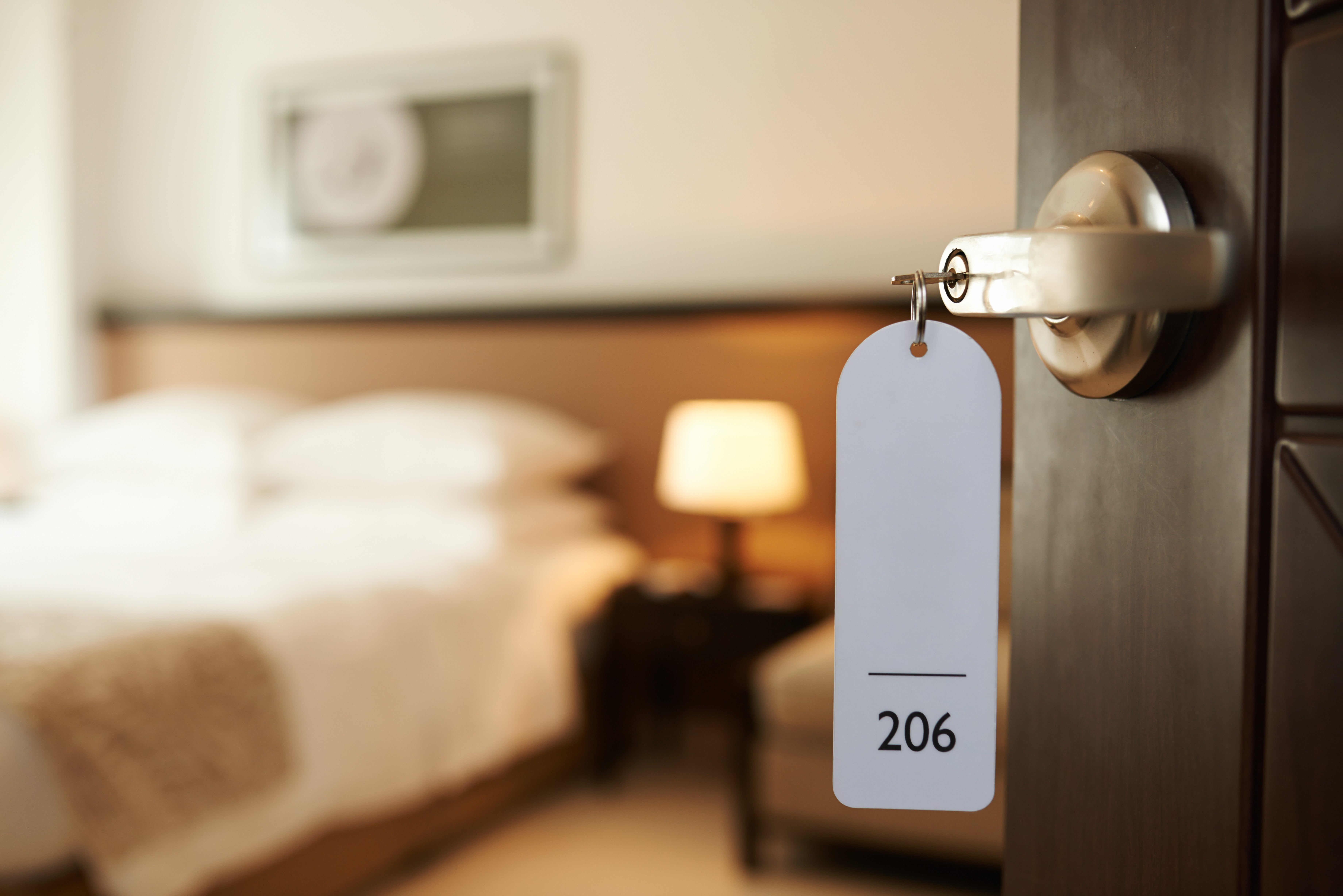 Hotellrom med åpen dør og en kopp hengende med romnummeret 206