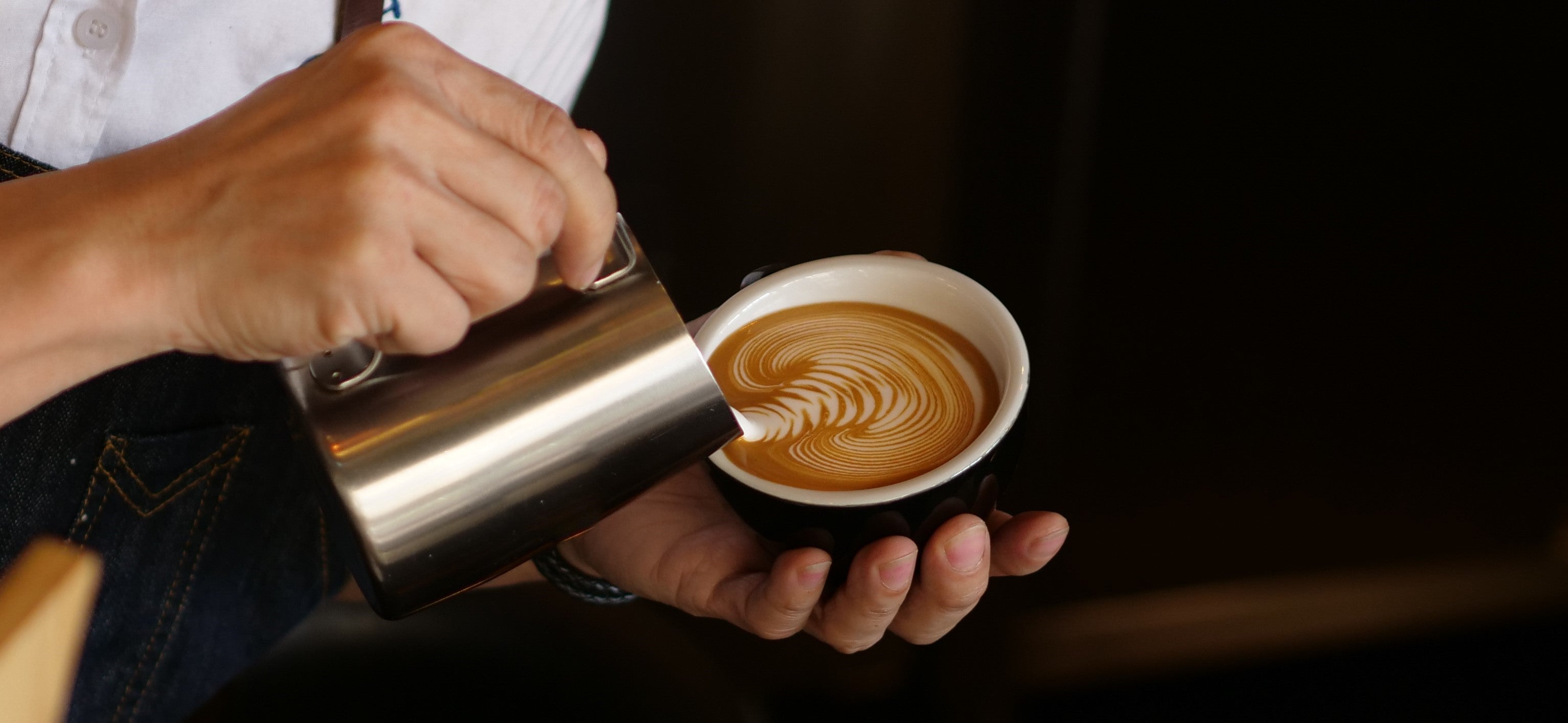 En arbetare som serverar cappuccino och ritar en blomma på toppen.