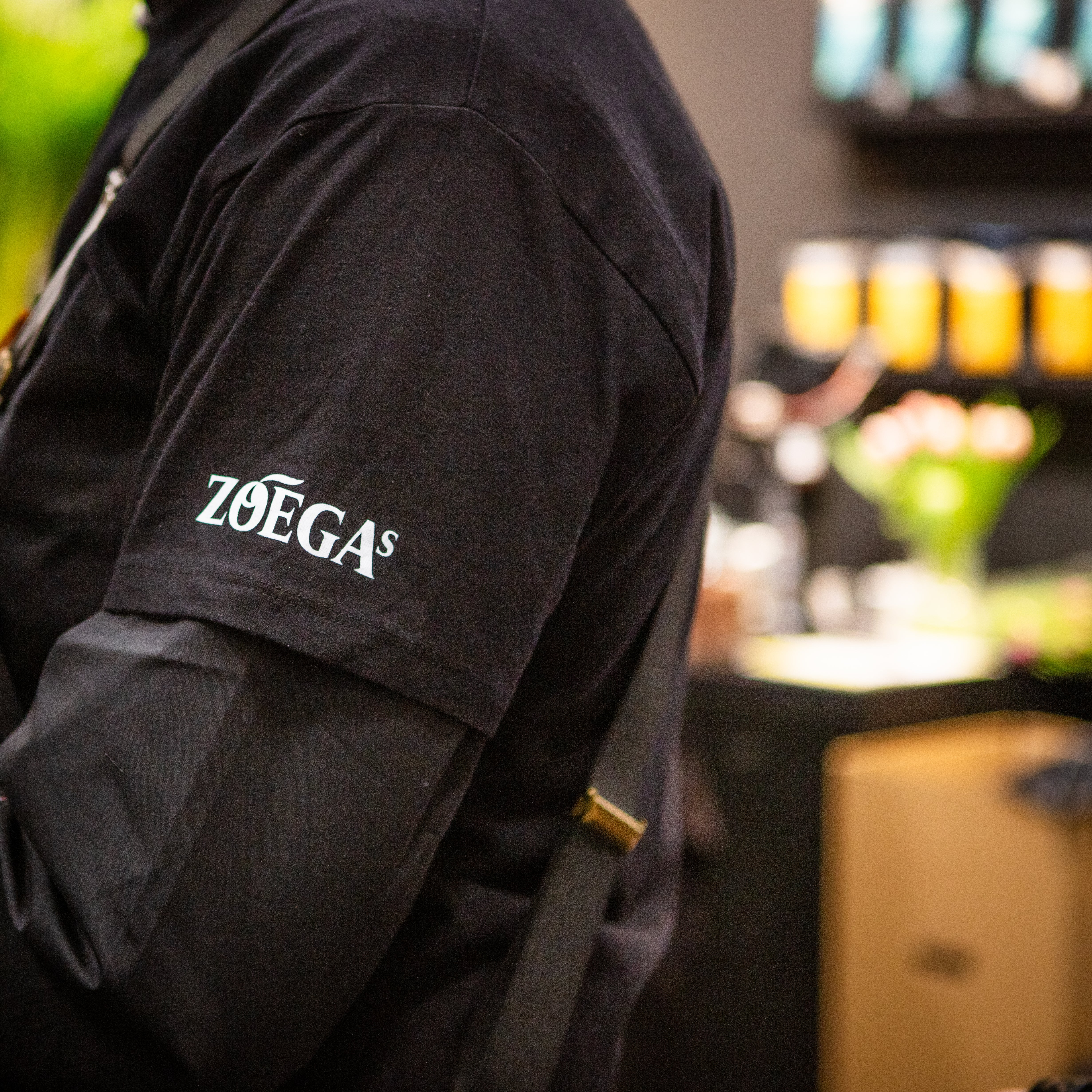 En kaffearbetare med en svart T-shirt och Zoégas-logotypen på armen