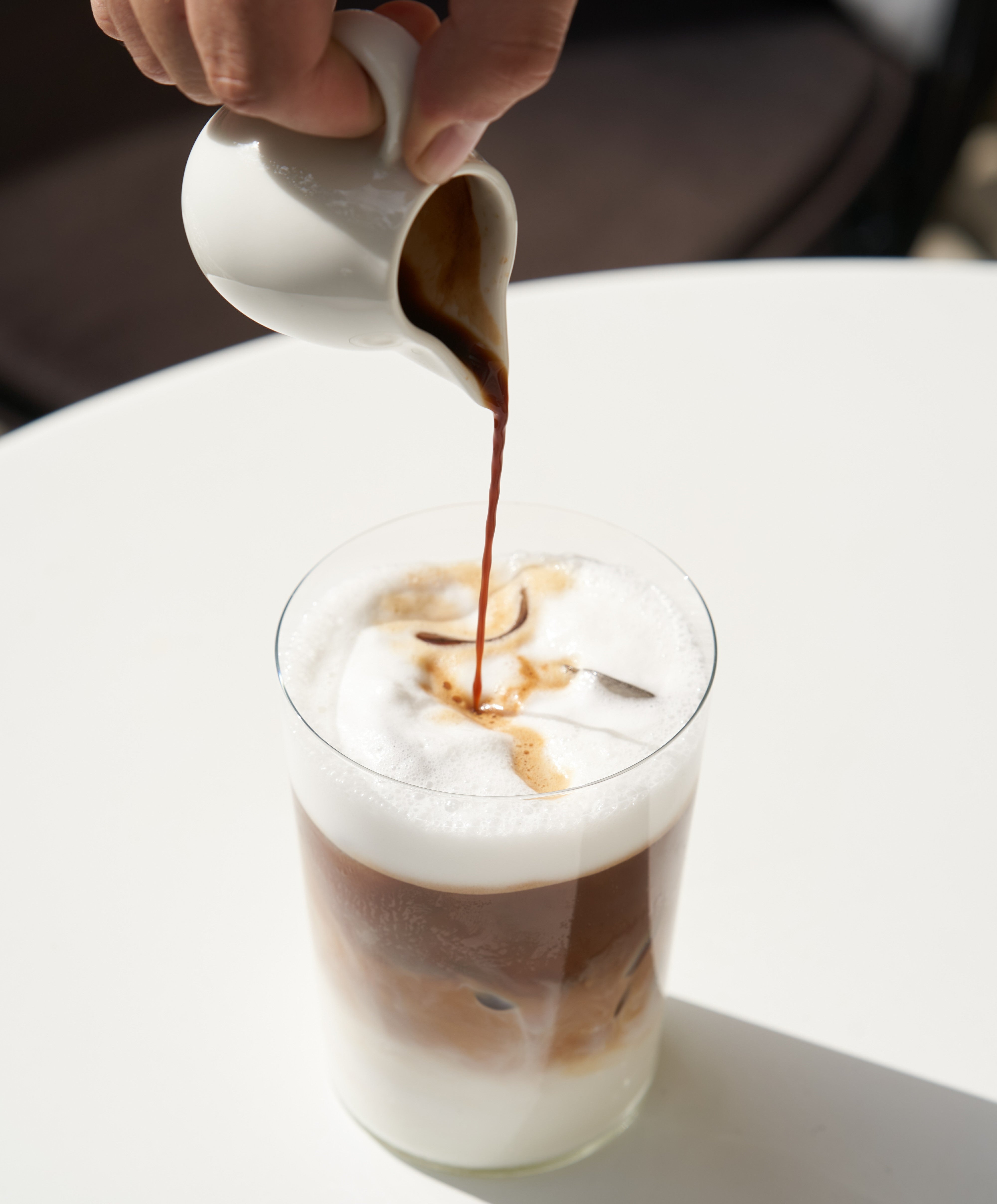 En latte macchiato som serveras på ett vitt bord