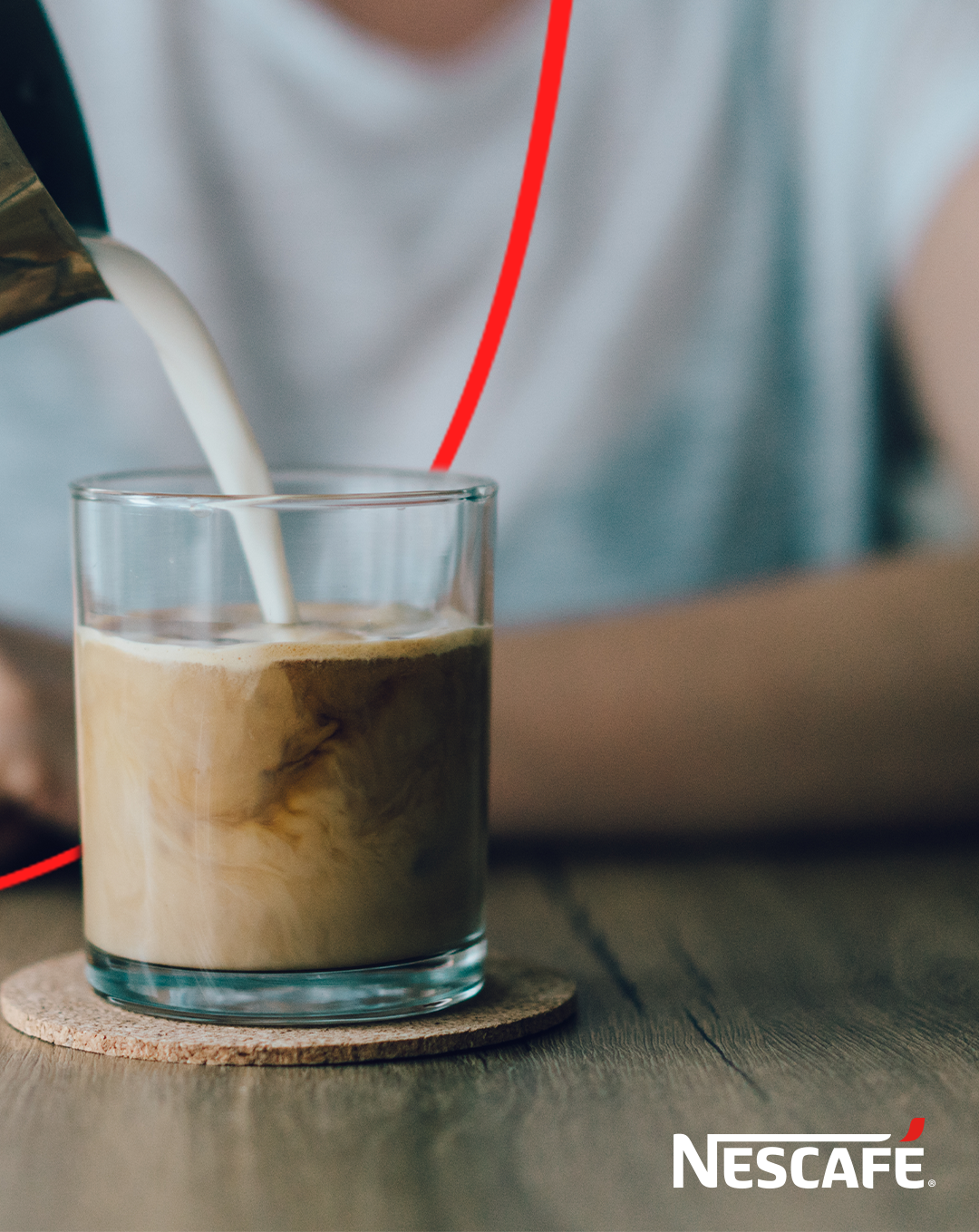 Café Nescafé i ett glas med mjölk som hälls i
