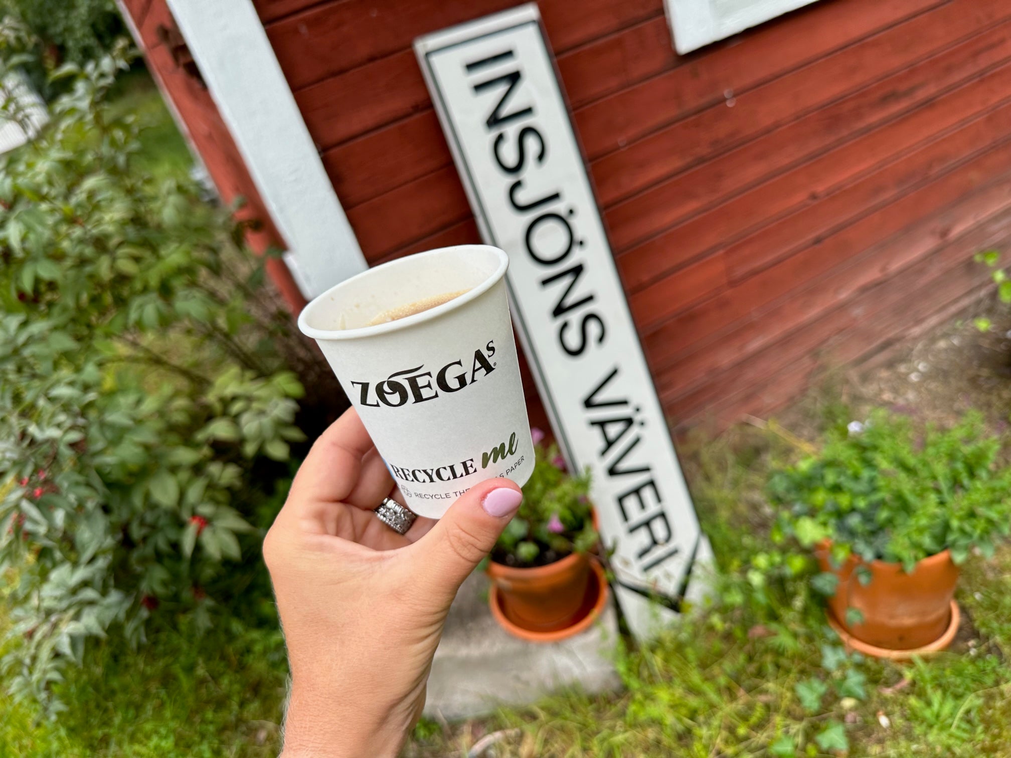Kvinna håller upp en take away Zoégas mugg