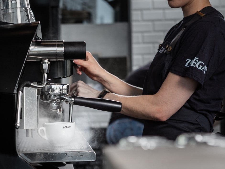 Barista med Zoégas t-skjorte tilbereder kaffe