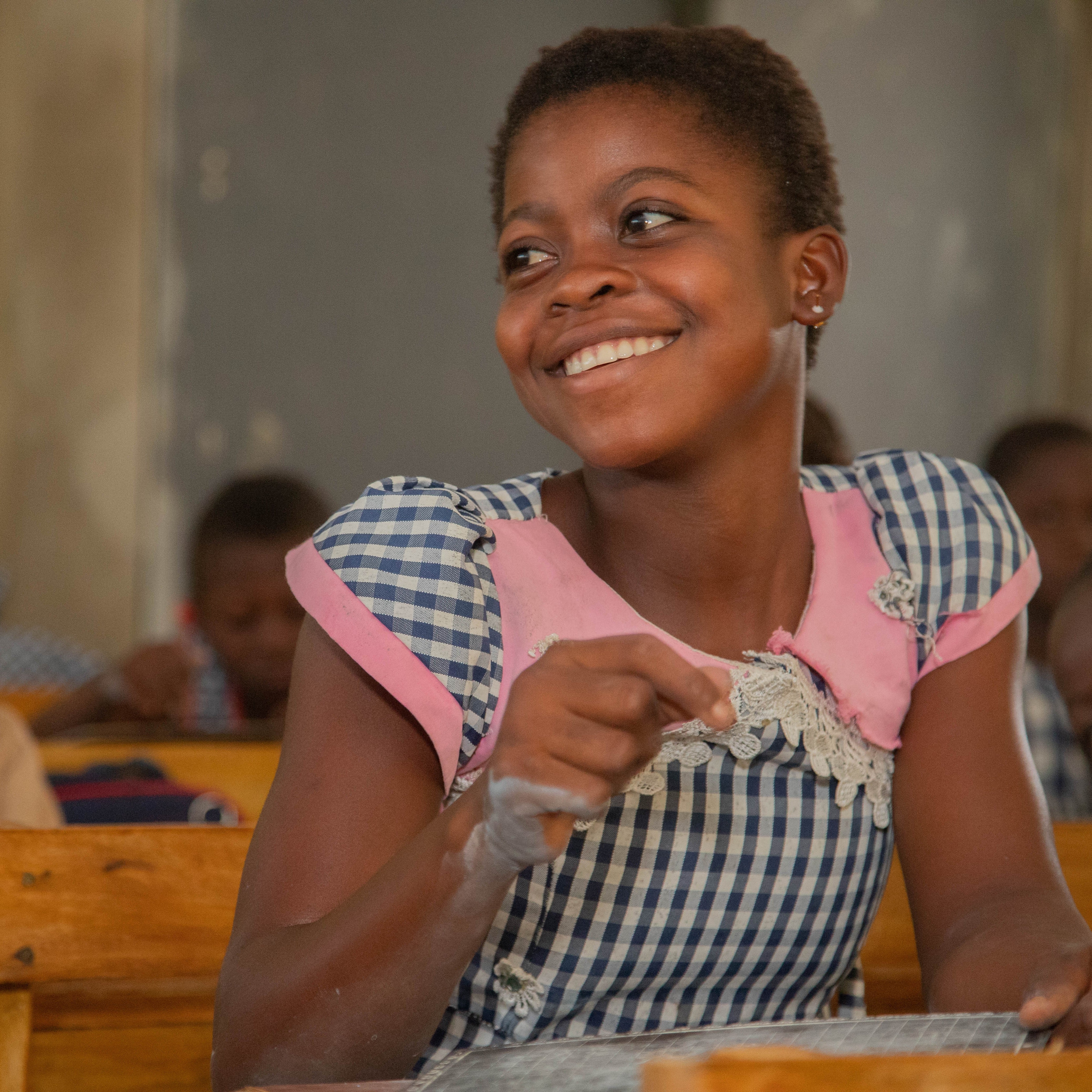 Flicka som sitter och tittar åt sidan med ett leende.