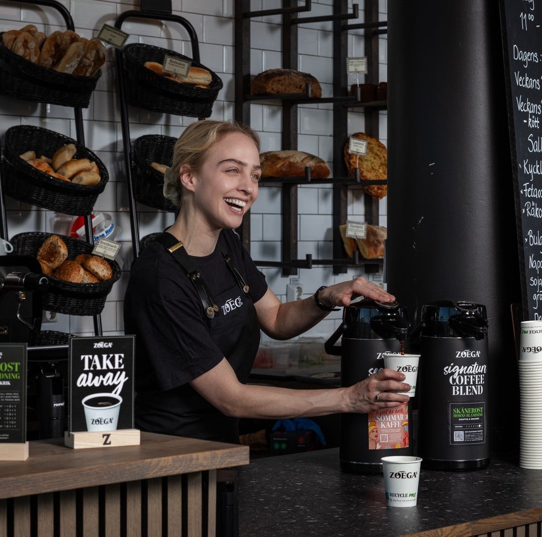 flicka ler medan hon serverar Zoegas Cooffe Blend-kaffe
