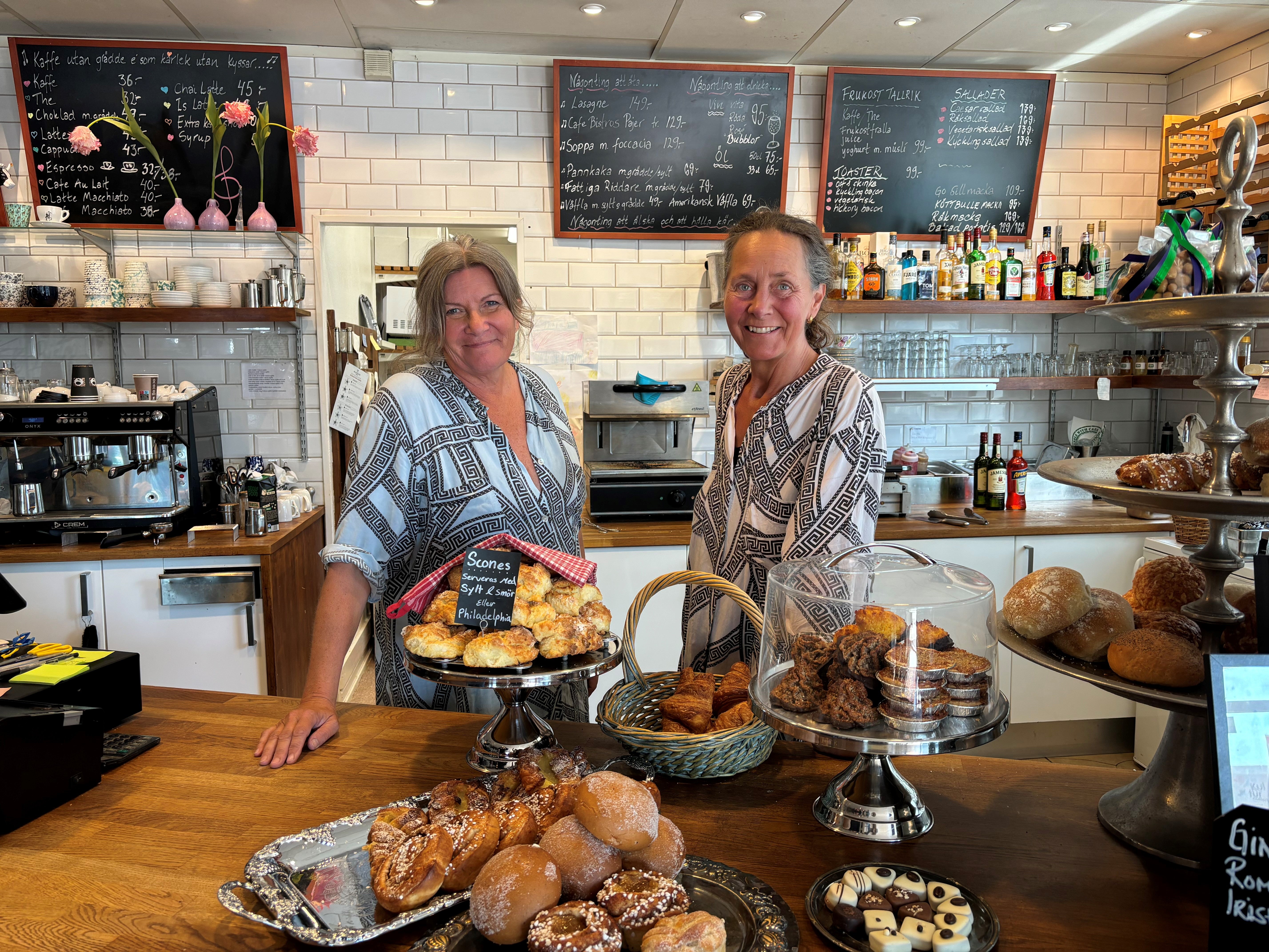 Kvinna som sitter vid bordet med en kopp kaffe, croissant och en bit tårta