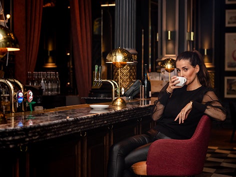 Flicka som sitter i en barfåtölj och njuter av sitt Zoeg-kaffe