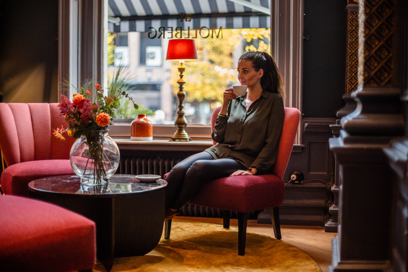 flicka sitter i caféfåtölj och njuter av sin kopp Zoegas-kaffe