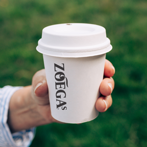 zoegas pappmugg i hand på fotbollsplan