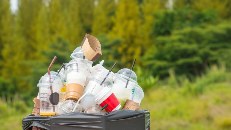 Soptunna full av plast mitt i naturen