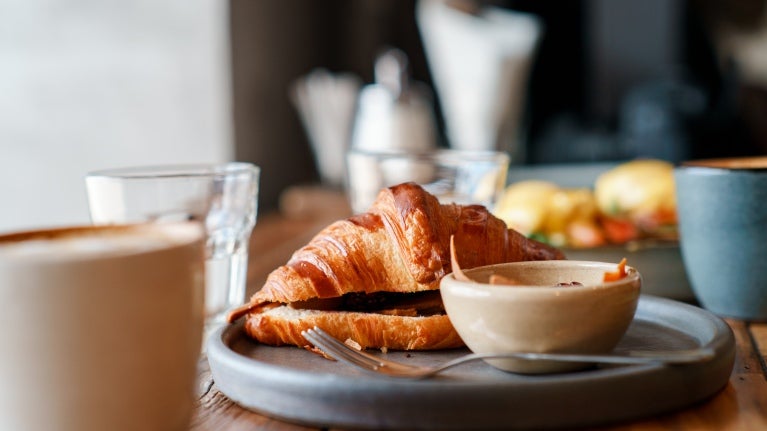 En tallerken med en kopp kaffe og croissant