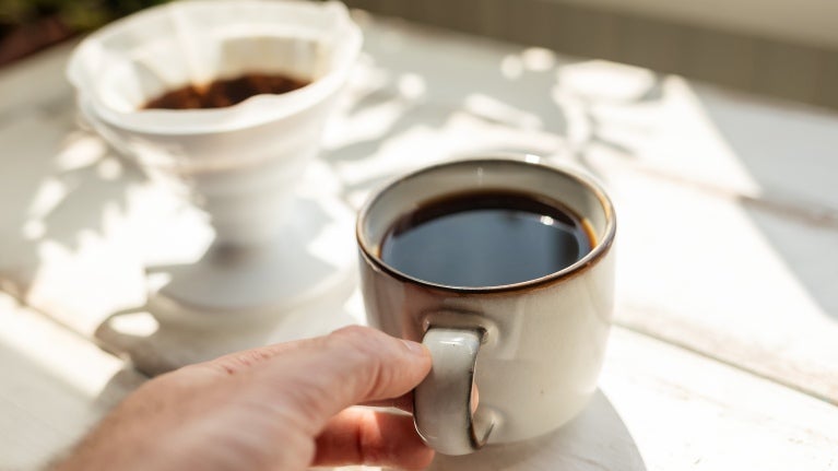 En kopp svart kaffe på vitt träbord