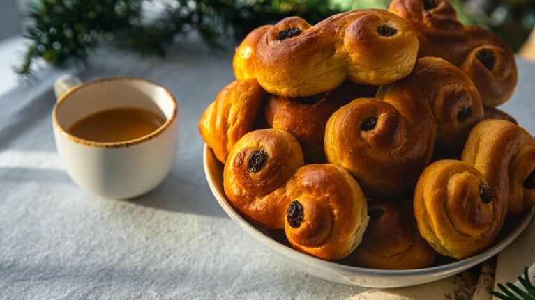Et bord med en kopp kaffe og en tallerken safranboller