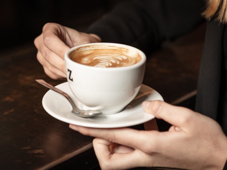 Kvinna håller i en Zoégas kopp med cappucino