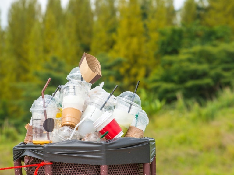 Soptunna full av plast mitt i naturen