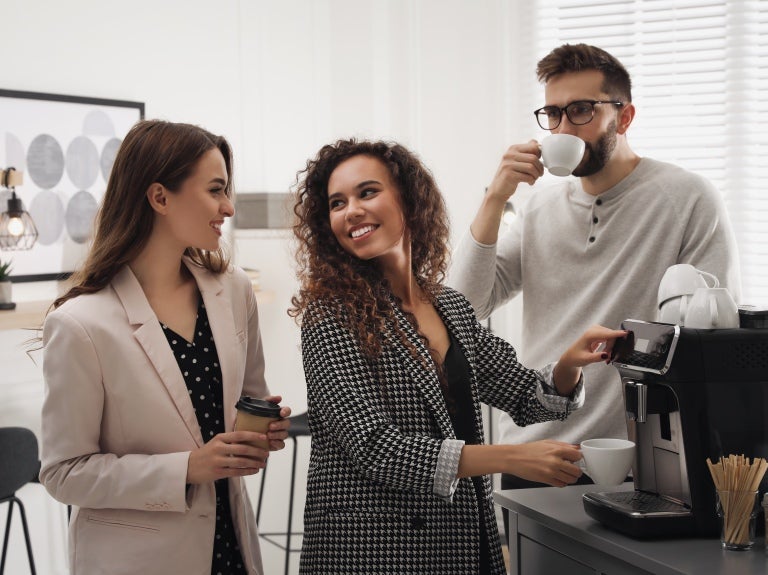 Kollegor på kontoret som serverar sig kaffe.