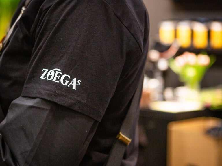 En kaffearbetare med en svart T-shirt och Zoégas-logotypen på armen
