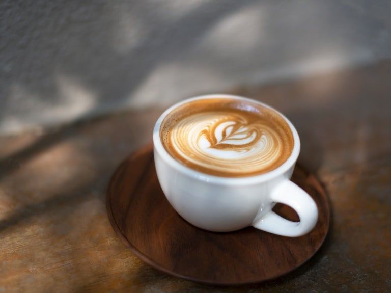 En cappuccino i en kopp med en träbricka