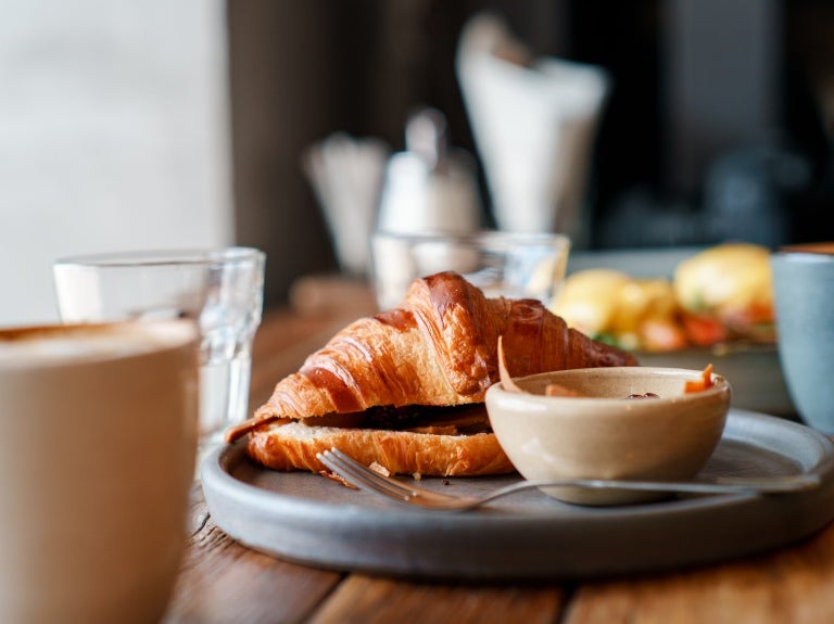 Ett träbord med en tallrik med croissanter och en kaffekopp
