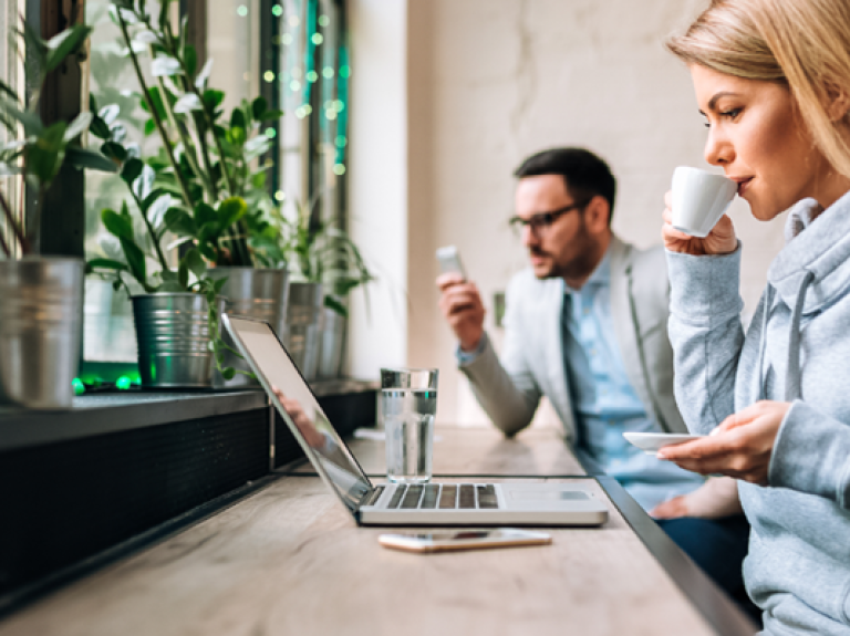 Medarbejdere arbejder og nyder en kop kaffe på arbejdet