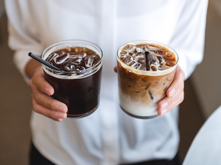 Kvinne som holder frem to glass iskaffe
