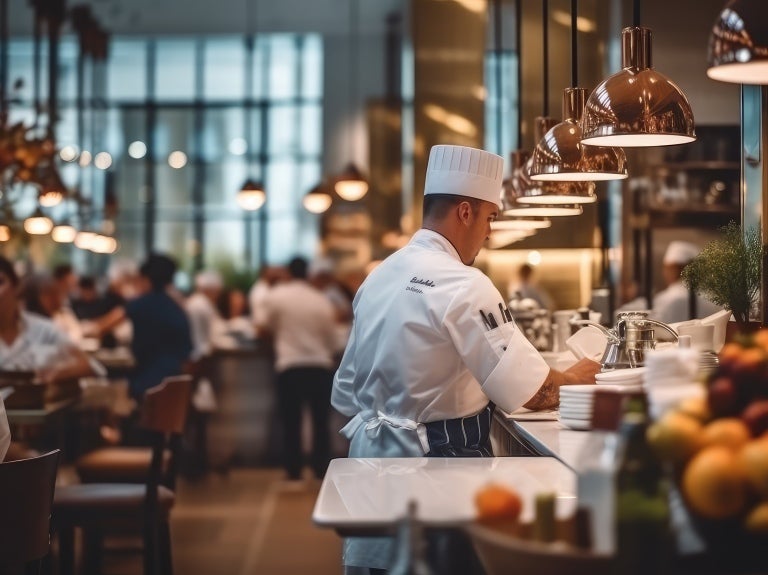 En restaurang med sittande kunder som njuter av sina måltider och en kock som står vid disken