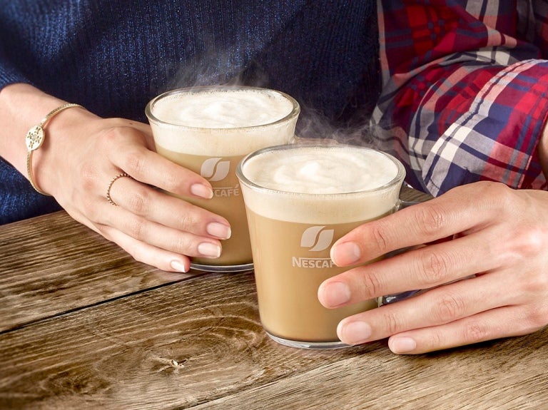 To latte i gjennomsiktige glass med Nescafé-logoen