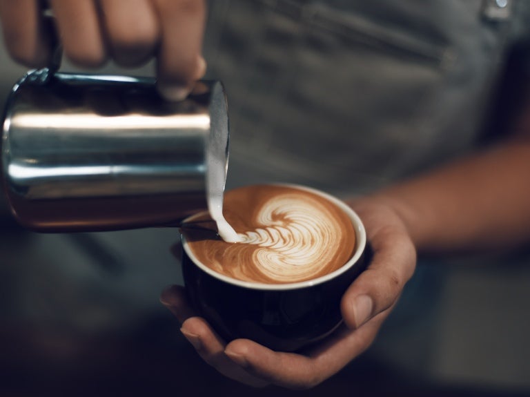 Cappuccino tarjoillaan kahvimukissa.