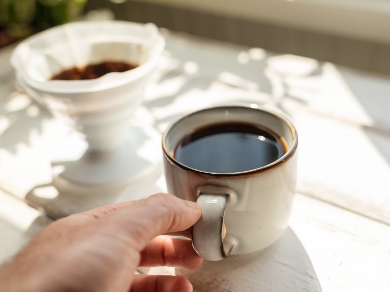 En kopp svart kaffe på vitt träbord