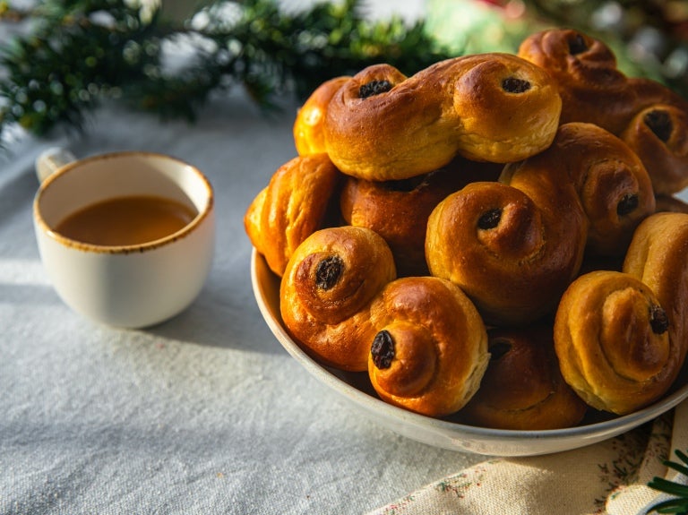 Et bord med en kopp kaffe og en tallerken safranboller