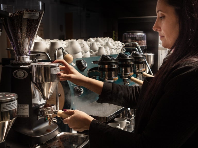 kvinna serverar Zoegas-kaffe från en industriell kaffemaskin