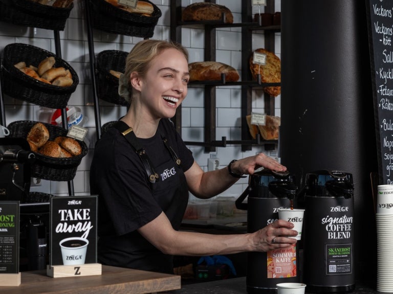 flicka ler medan hon serverar Zoegas Cooffe Blend-kaffe