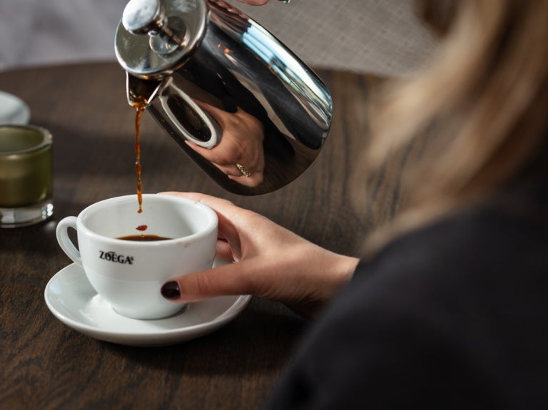 Man greppar en kopp Zoégas kaffe