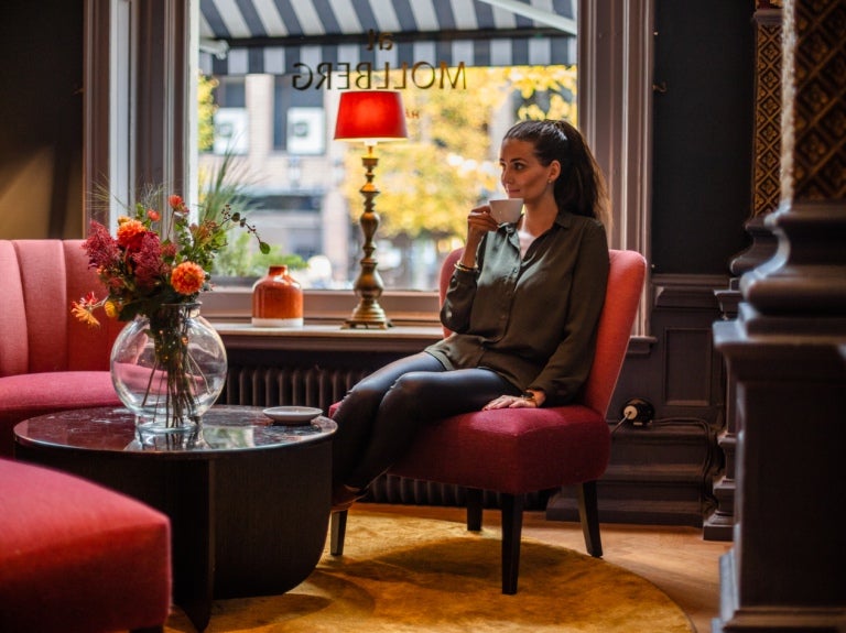 flicka sitter i caféfåtölj och njuter av sin kopp Zoegas-kaffe