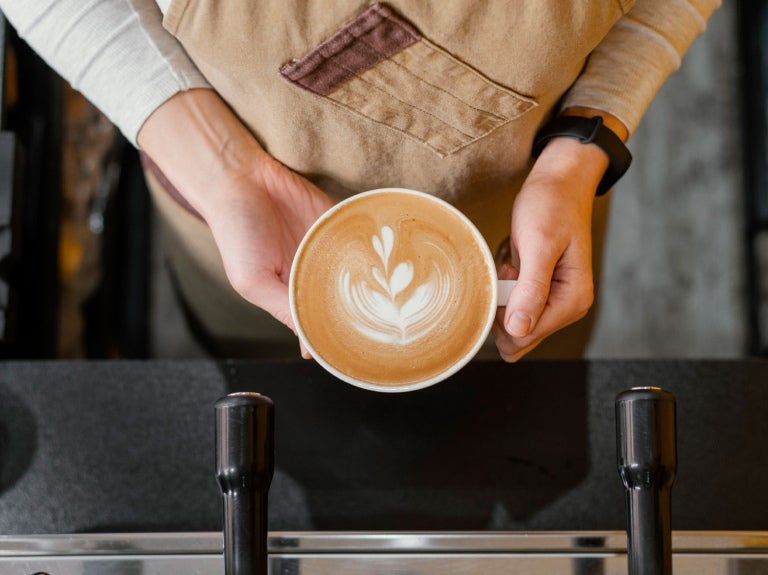 kopp med cappuccino i händer