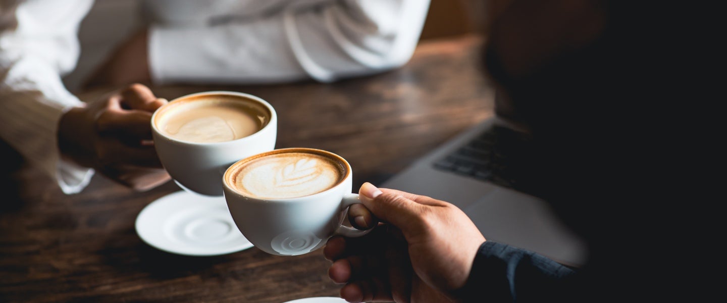 Personer som dricker cappuccino med sina bärbara datorer på bordet.