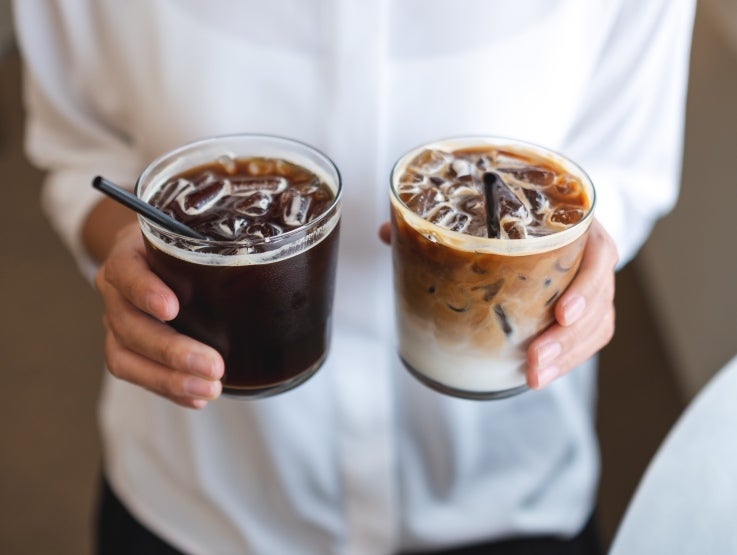 Kvinne som holder frem to glass iskaffe