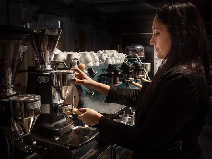 kvinna serverar Zoegas-kaffe från en industriell kaffemaskin