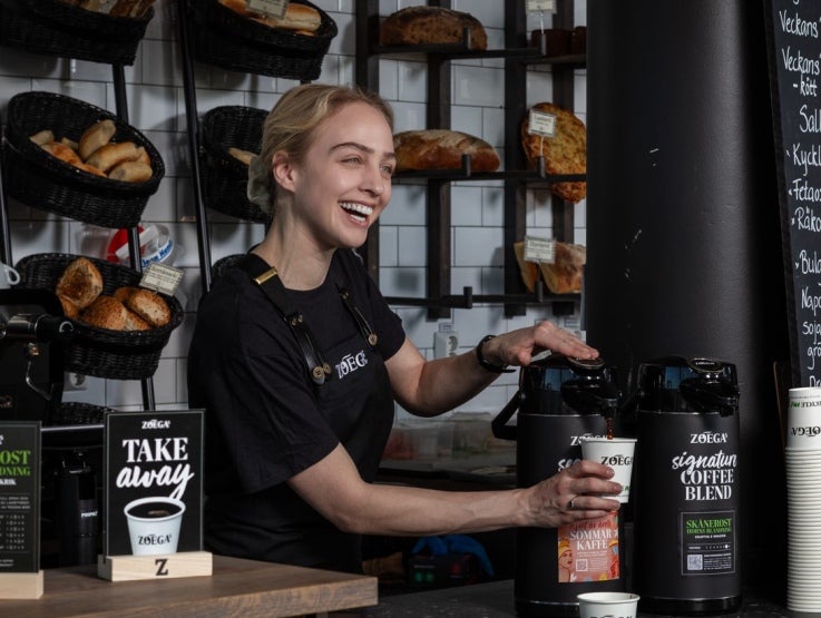 flicka ler medan hon serverar Zoegas Cooffe Blend-kaffe