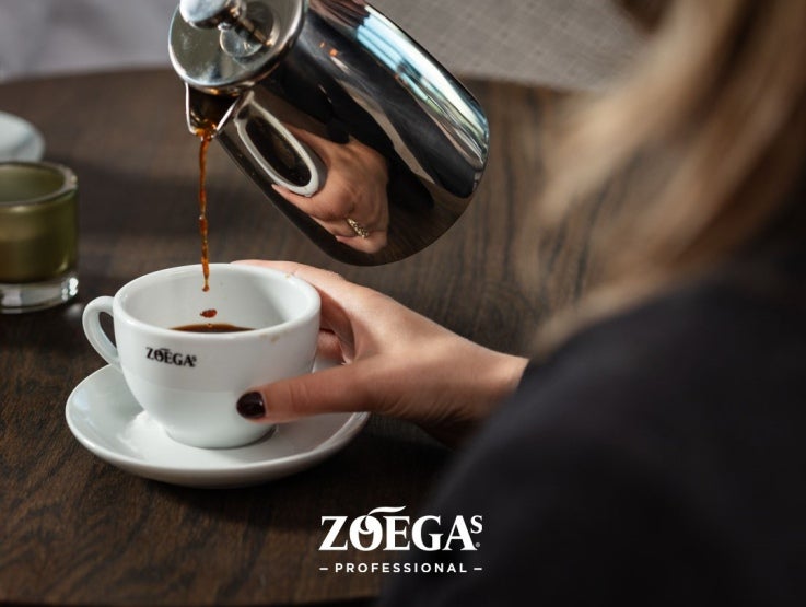 Servitris häller upp kaffe i Zoégas mugg