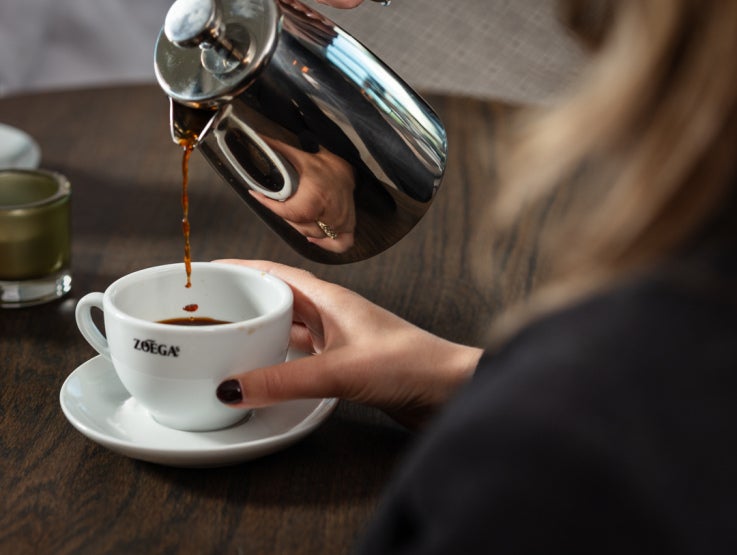 Man greppar en kopp Zoégas kaffe
