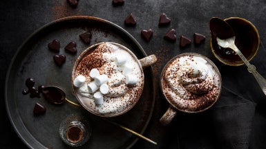 varm choklad i muggar med grädde och marshmallows