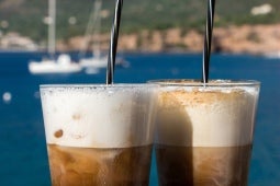 Drycker i glas med skum och sugrör. Utsikt över vatten med båtar i bakgrunden