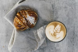 ett glas latte och en kanelsnäcka