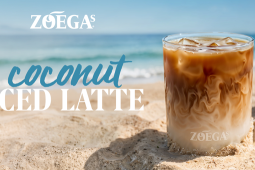 zoegas iced coconut latte i glas på en strand med kokosnöt