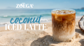 zoegas iced coconut latte i glas på en strand med kokosnöt