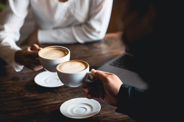 Personer som dricker cappuccino med sina bärbara datorer på bordet.