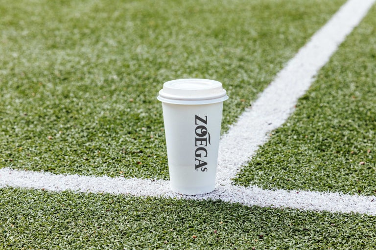 zoegas pappmugg i närbild på fotbollsplan